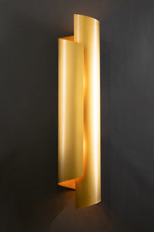  A metal wall sconce with a satin brass finish, featuring an up and down lighting effect, mounted on a dark background.