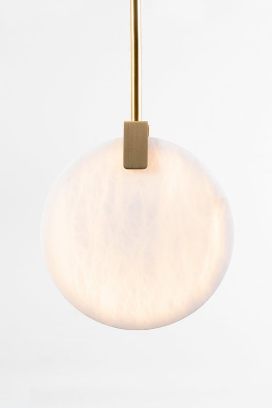 A satin brass finished LED pendant light fixture with a round alabaster shade, suspended from the ceiling by a small cylindrical fitter.