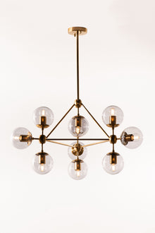  A sophisticated chandelier with a satin brass finish and smoke glass globes, suspended in a state of descent with multiple adjustable stems.