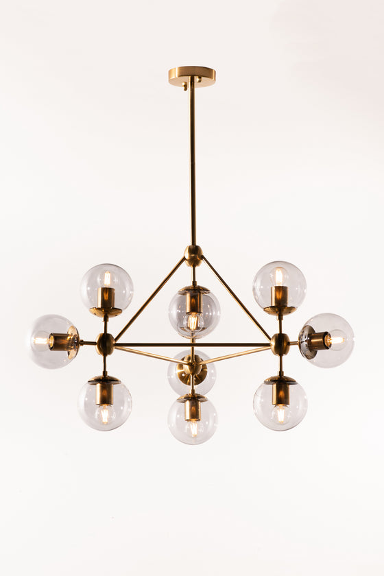 A sophisticated chandelier with a satin brass finish and smoke glass globes, suspended in a state of descent with multiple adjustable stems.