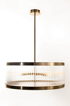 A contemporary satin brass round pendant light fixture with clear glass shade, designed for ceiling mounting.