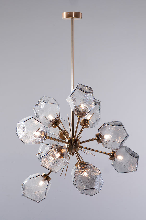 A contemporary style chandelier with a satin brass finish and geometric smoke glass geodes, creating a starburst pattern.