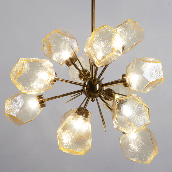 A contemporary style chandelier with a satin brass finish and geometric amber glass geodes, creating a starburst pattern.