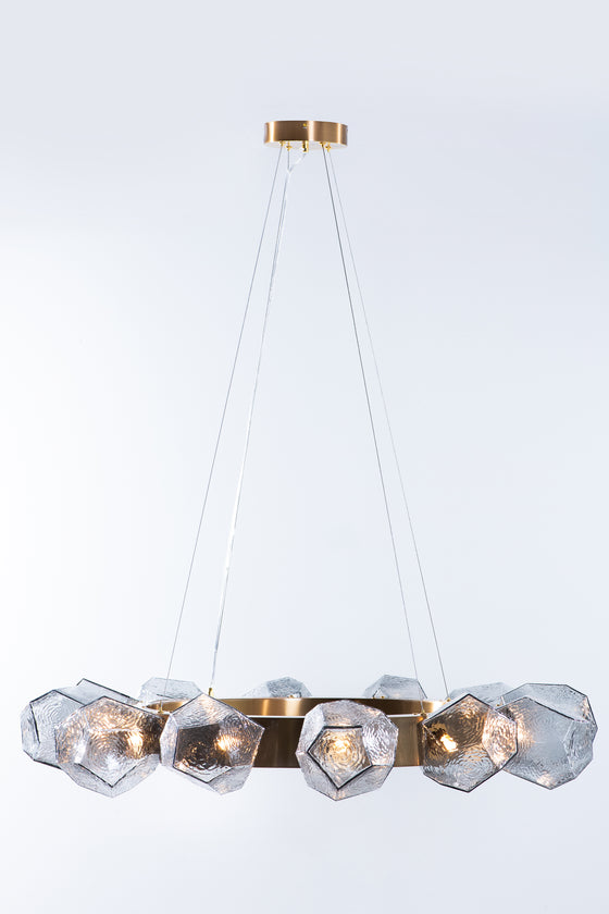A contemporary geometric glass chandelier with a satin brass finish, featuring clear glass geometric shapes.