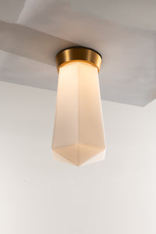  A LED ceiling light fixture with a geometric shape and a matte opal glass shade, featuring a satin brass finish.