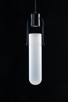  A matte black modern pendant light with a frosted glass shade against a black background.