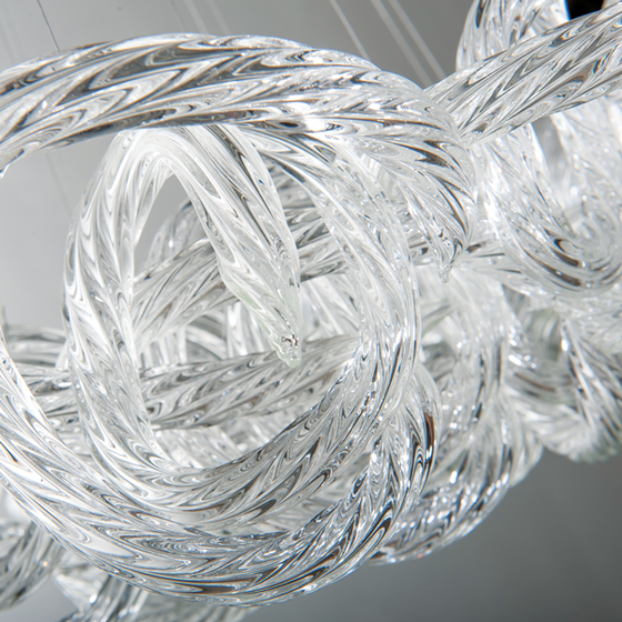 View of curved glass details of the Loren Clear Rope Glass Chandelier on a darker background