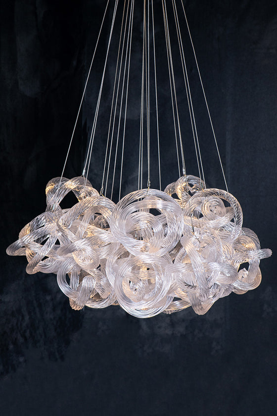 A clear rope glass chandelier with intricate glass rope knots hanging from fine, thin cables, illuminated from lights above.