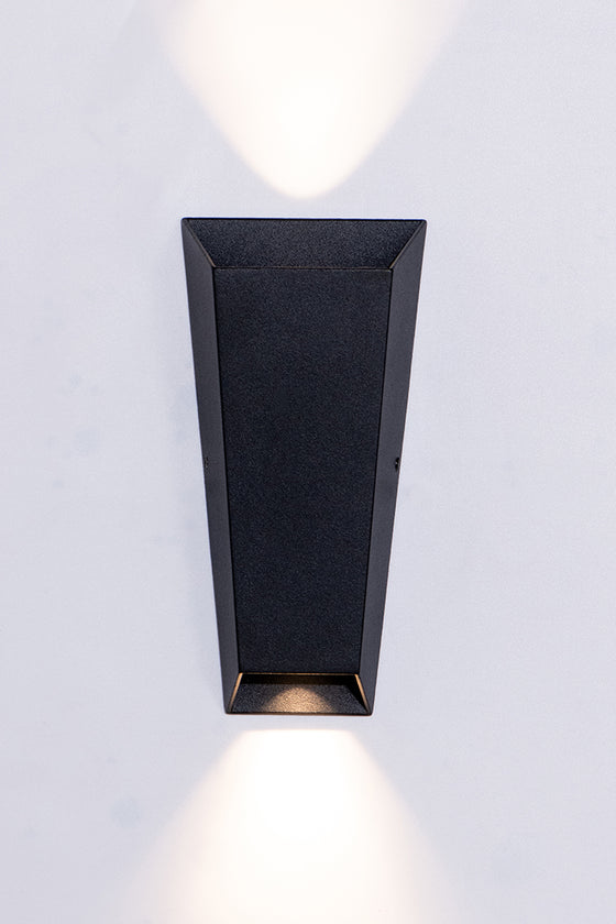 A modern black wall sconce with tapered body, casting light both up and down.
