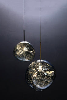  Two bubble-shaped pendant light fixtures with a metallic plated mirror shade, suspended by cords from a matching metallic canopy, displayed against a dark background.