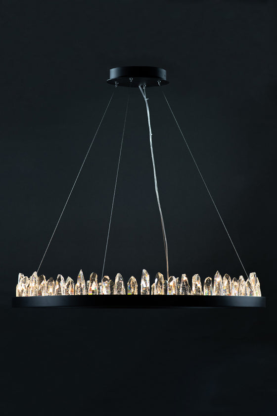 A contemporary round crystal chandelier with a matte black finish and integrated LED lighting, featuring a line of crystal geodes, suspended by multiple cables against a dark background.