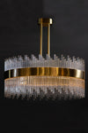 A modern satin brass chandelier with clear glass rods, hanging against a dark background.