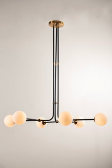  A modern glass globe chandelier with a matte black frame and satin brass accents, featuring opal matte white glass shades.
